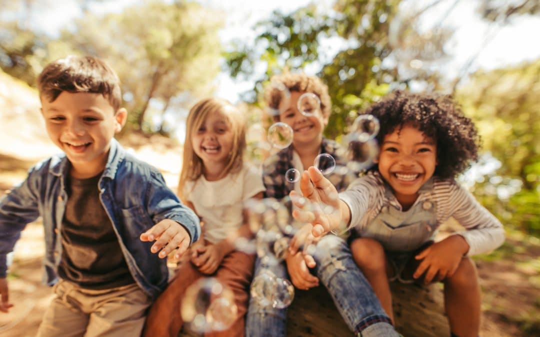 Kids playing with bubbles with healthy teeth after dental care with childrens dental insurance in Brooklyn NY